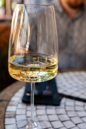 Sipping on a chilled white wine while relaxing at a quaint cafe table in the sun.の写真素材