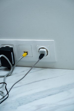 Multiple cords plug into a sleek electrical outlet, showcasing a blend of functionality and design.