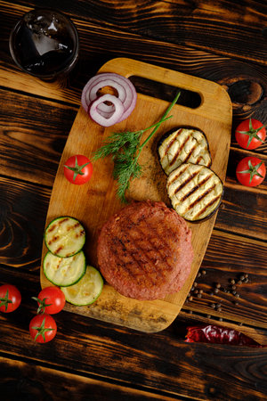Juicy burger patty paired with grilled zucchini and eggplant, garnished with fresh herbs and onions.の写真素材