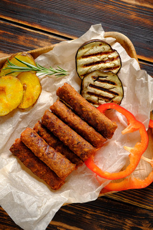 Savory meat rolls nestled beside fresh grilled eggplant and crispy plantain chips on a rustic tray.
