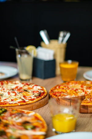 Colorful array of pizzas topped with various ingredients served alongside refreshing beverages.の写真素材
