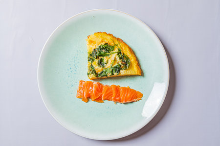 A vibrant slice of frittata accompanied by rich salmon offers a delightful breakfast option.の写真素材