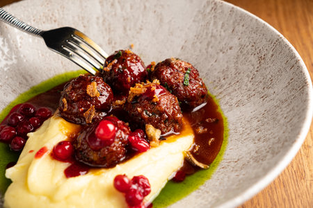 Delicious Swedish meatballs accompany fluffy mashed potato and rich sauce, garnished with berries.の写真素材