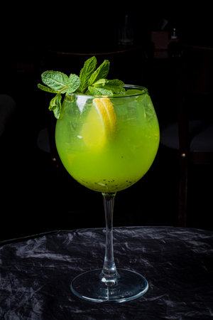A refreshing cocktail blends vivid green hues with mint and lemon, served in a stylish glass.の写真素材