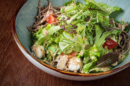 A vibrant bowl of soba noodles, fresh greens, herbs, and tomatoes.