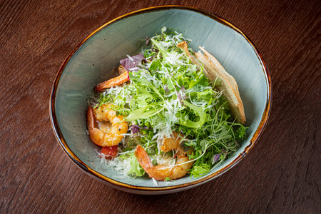 A colorful bowl features succulent shrimp atop a bed of crisp greens with a sprinkle of cheese.の写真素材