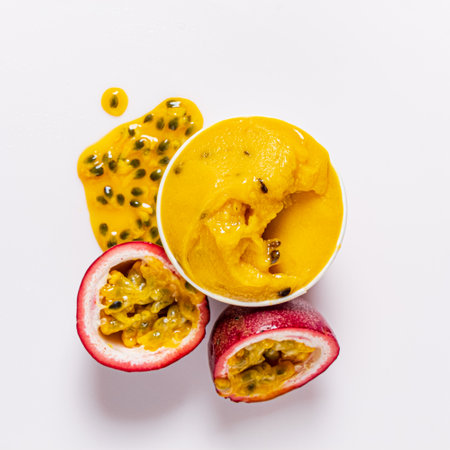 Mango passion fruit sorbet sits in a bowl next to a halved fruit, highlighting its juicy goodness.の写真素材