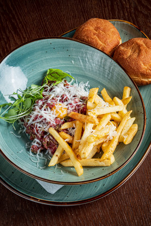 A colorful plate features minced beef with cheese, golden fries, and fresh greens.