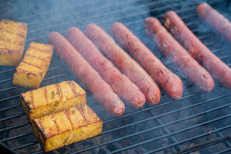 Juicy sausages and golden cornbread sizzle on the grill, creating a mouthwatering feast outdoors.の写真素材