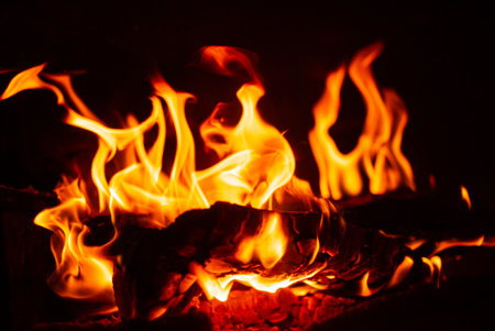 Bright, flickering flames rise and curl passionately, casting a glow on the dark surroundings.の写真素材