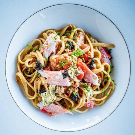 A rich bowl of linguine topped with fresh crab, caviar, and delicate garnishes awaits!の写真素材