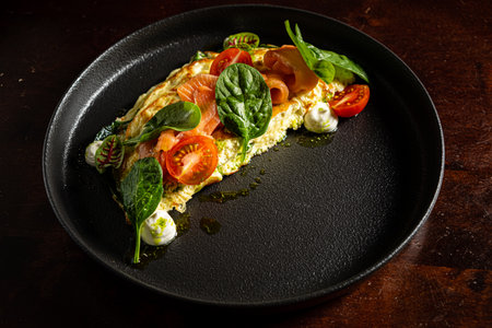 A stunning omelette with tomatoes, smoked salmon, and spinach showcases culinary artistry.の写真素材