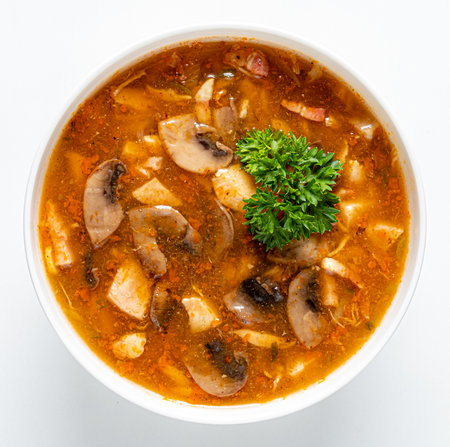 A flavorful bowl of hearty soup brimming with mushrooms and vegetables garnished with fresh herbs.の写真素材
