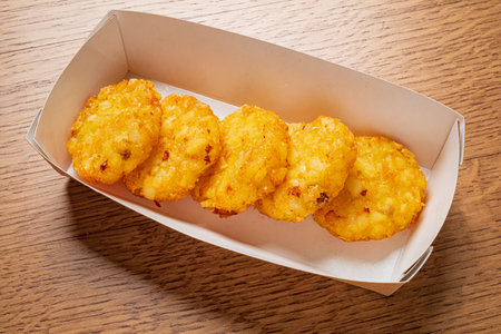 Five golden potato snacks arranged neatly in a cardboard container exude deliciousness.の写真素材