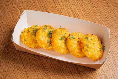 Five perfectly fried potato fritters are arranged in a serving tray, showcasing their crispiness.の写真素材