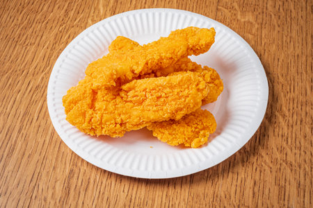 Delightful chicken tenders glisten with a crispy coating, inviting hunger at mealtime.の写真素材