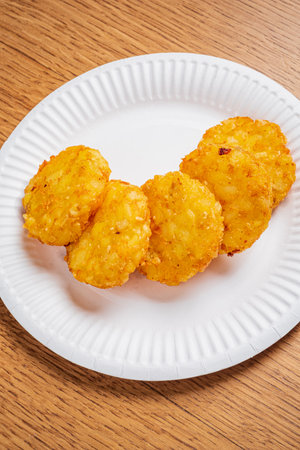 A plate holds several golden, crispy potato rounds, perfect for snacking at any event.の写真素材