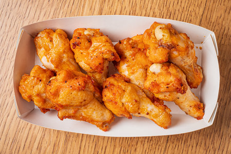 Golden brown chicken wings perfectly fried, served in a convenient takeout box for sharing.の写真素材