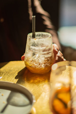 A hand holds a chilled drink, capturing a moment of leisure in bright light.