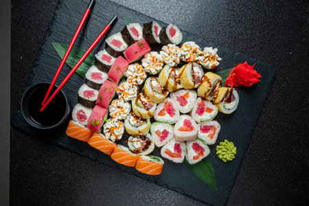 A vibrant array of sushi rolls with diverse colors and flavors on a dark surface.の写真素材