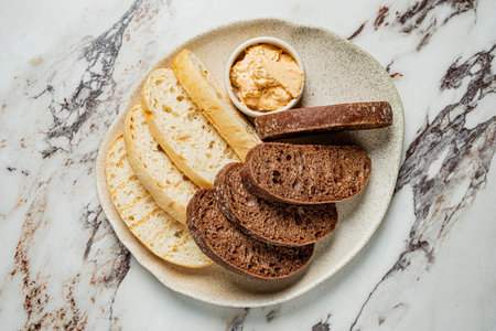 A variety of fresh breads accompanied by a rich and creamy spread awaits to be enjoyed.の写真素材