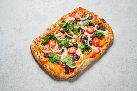 A delicious square pizza topped with tomatoes, onions, jalapenos, and herbs, ready to be enjoyed.の写真素材
