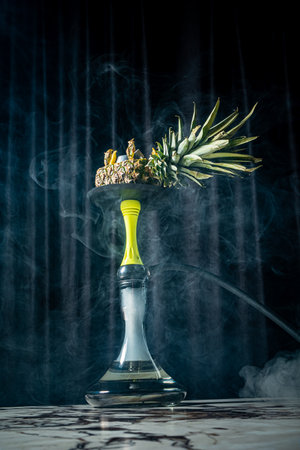 Savor the rich flavors and smoke of a crafted pineapple hookah in a gentle mist.の写真素材