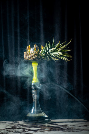 A vibrant hookah topped with fresh pineapple fills the air with aromatic smoke.