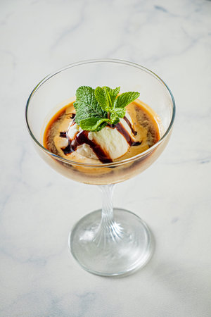 A rich blend of flavors in a glass, topped with ice cream, chocolate drizzle, and mint.