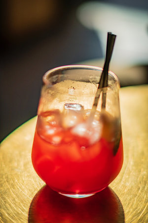Refreshing drink filled with ice and vibrant colors catches the glow of ambient light in a cozy bar.の写真素材