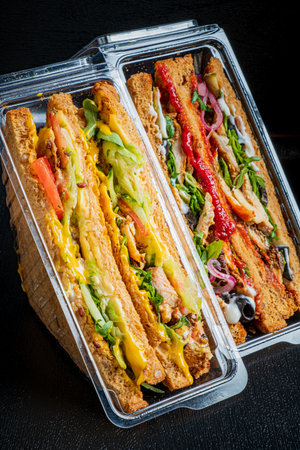 Colorful sandwiches with fresh veggies and meats are neatly packed in clear containers for lunch.の写真素材