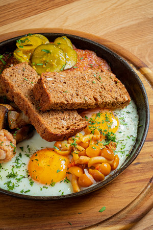 A delicious breakfast features golden eggs, fluffy beans, tangy pickles, and hearty bread.の写真素材