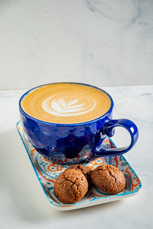 Enjoy expertly crafted coffee with intricate latte art and warm cookies.の写真素材