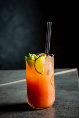 A vibrant tropical cocktail filled with ice and lime slices captures the essence of relaxation.の写真素材