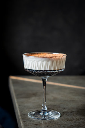 A creamy dessert topped with cocoa powder sits elegantly in a stylish glass on a rustic table.の写真素材