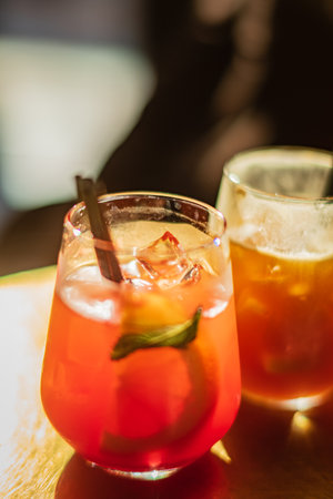 Refreshing cocktails in vibrant colors are served at a wooden table, capturing the evening's charm.の写真素材