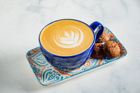 Enjoying a rich latte crowned with delicate foam art alongside a plate of scrumptious cookies.の写真素材