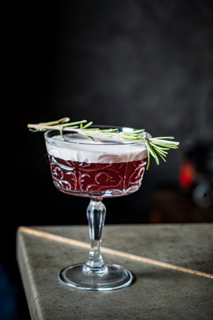 A stunning cocktail glows softly, garnished with rosemary and vibrant hues.の写真素材