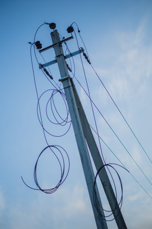 A tall utility pole stretches skyward with colorful wires forming artistic loops.