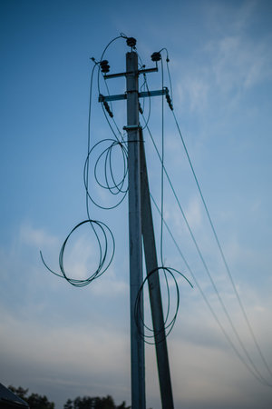 A utility pole silhouetted against a tranquil twilight sky, wrapped in wires and cables.