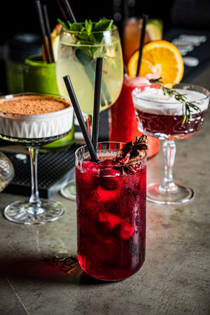 Vibrant cocktails in elegant glasses showcase the creativity of mixology at a busy bar.の写真素材