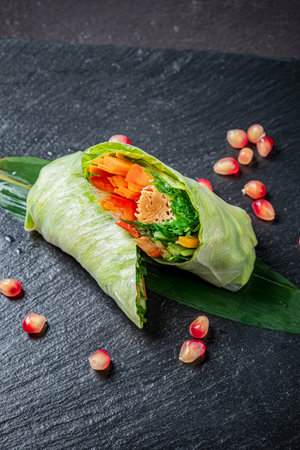 Vibrant spring rolls with crisp veggies and pomegranate seeds on slate.