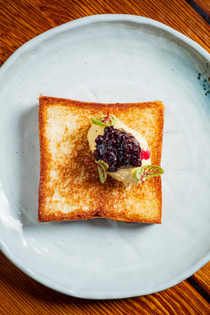 Crispy toast topped with creamy ice cream, berry compote, and delicate garnishes.の写真素材
