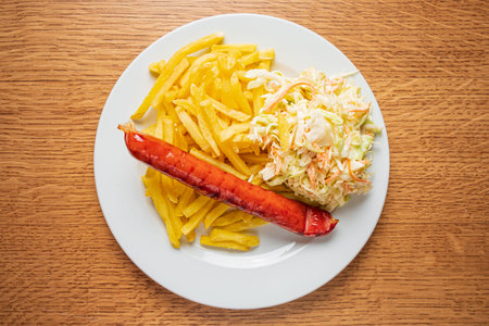 Golden fries, juicy grilled sausage, and creamy coleslaw on a white plate.