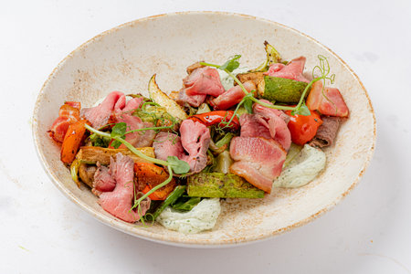 Tender roasted meats paired with vibrant grilled vegetables and fresh herbs create a colorful feast.の写真素材