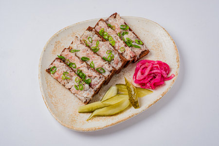 Slices of savory dish topped with green onions, accompanied by pickles and vibrant onions.の写真素材