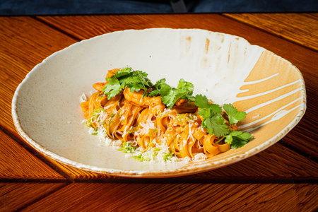 A vibrant plate of shrimp pasta with cilantro, beautifully presented on a rustic ceramic dish.の写真素材