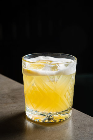 Refreshing citrus drink with ice and lemon, enjoyed in a cozy bar setting during the night.