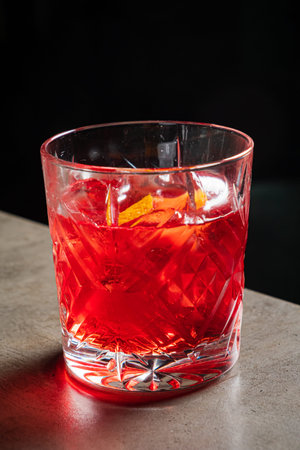 Reflecting elegance, a crystal glass holds a vibrant red cocktail adorned with citrus twists.