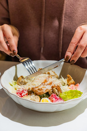 Hands skillfully cut into a vibrant salad filled with fresh vegetables and chicken.の写真素材
